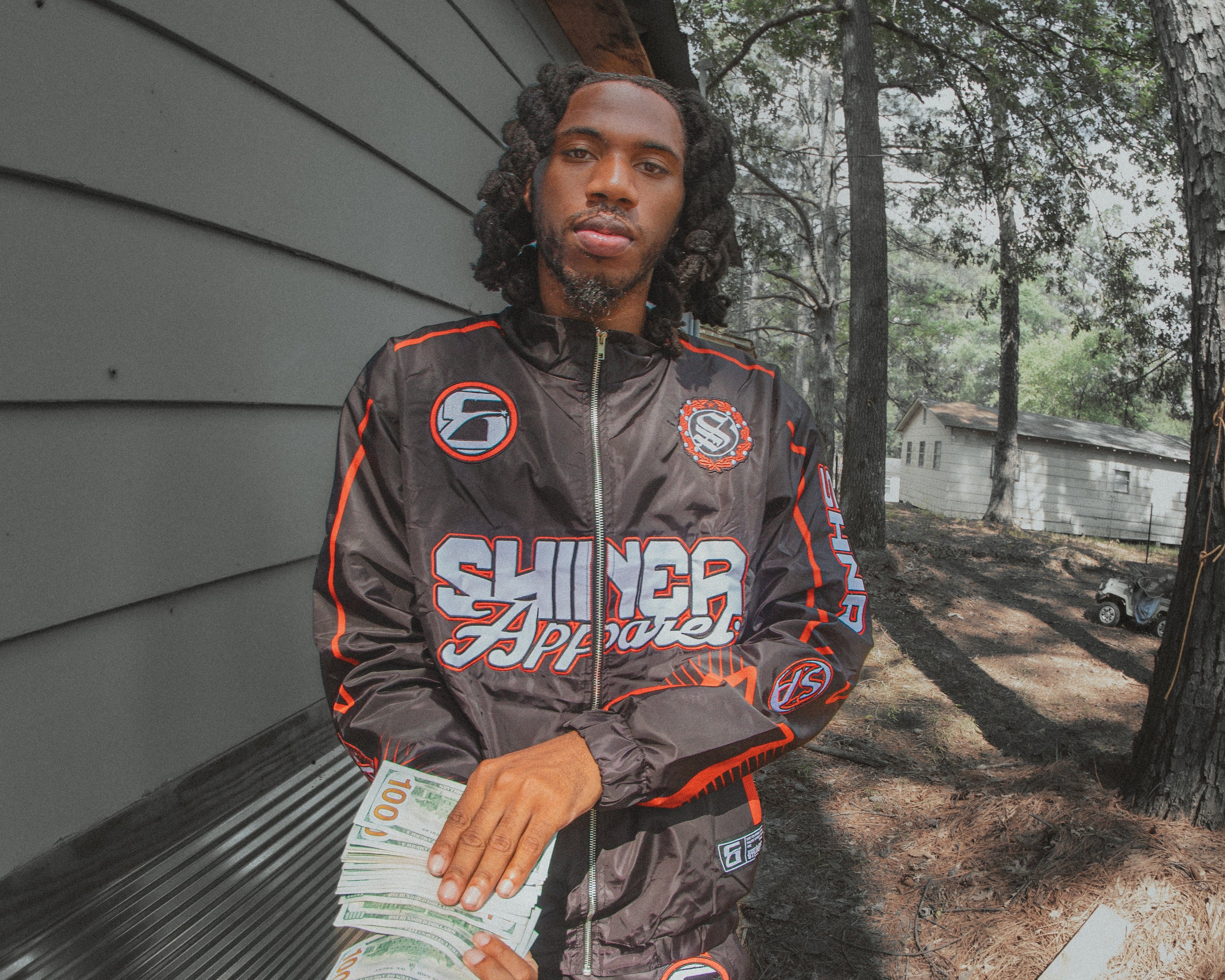 Person wearing a branded jacket holding money outdoors
